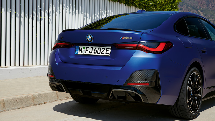 BMW i4 M50 G26 2021 BMW Individual Frozen Portimao Blue metallizzato Vista posteriore a tre quarti ferma vicino a recinto bianco