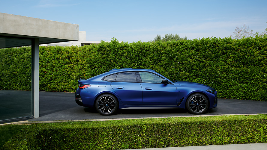 Vista posteriore della BMW i4 M50 G26 in 2021 movimento su una strada provinciale BMW i4 M50 G26 2021 BMW Individual Frozen Portimao Blue metallizzato Vista posteriore in movimento su una strada provinciale