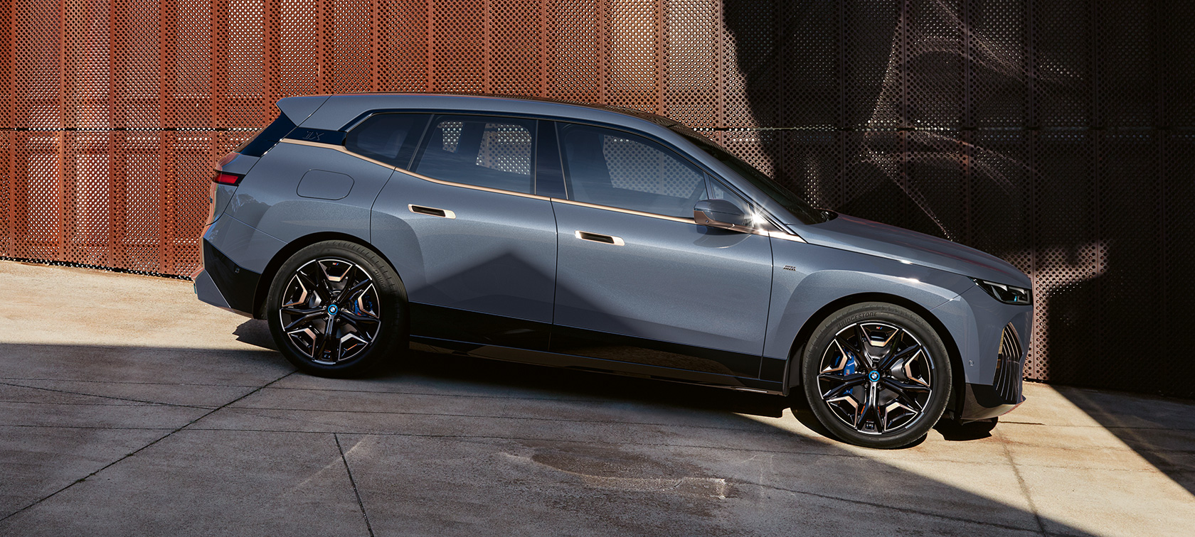 BMW iX M60 i20 2022 SUV elettrico BMW Individual Storm Bay metallizzato Vista laterale in parcheggio
