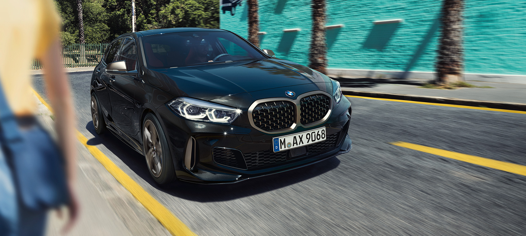 BMW M135i xDrive, vista anteriore a tre quarti F40. BMW M135i xDrive in Sapphire Black metallizzato, vista anteriore a tre quarti, in movimento F40.