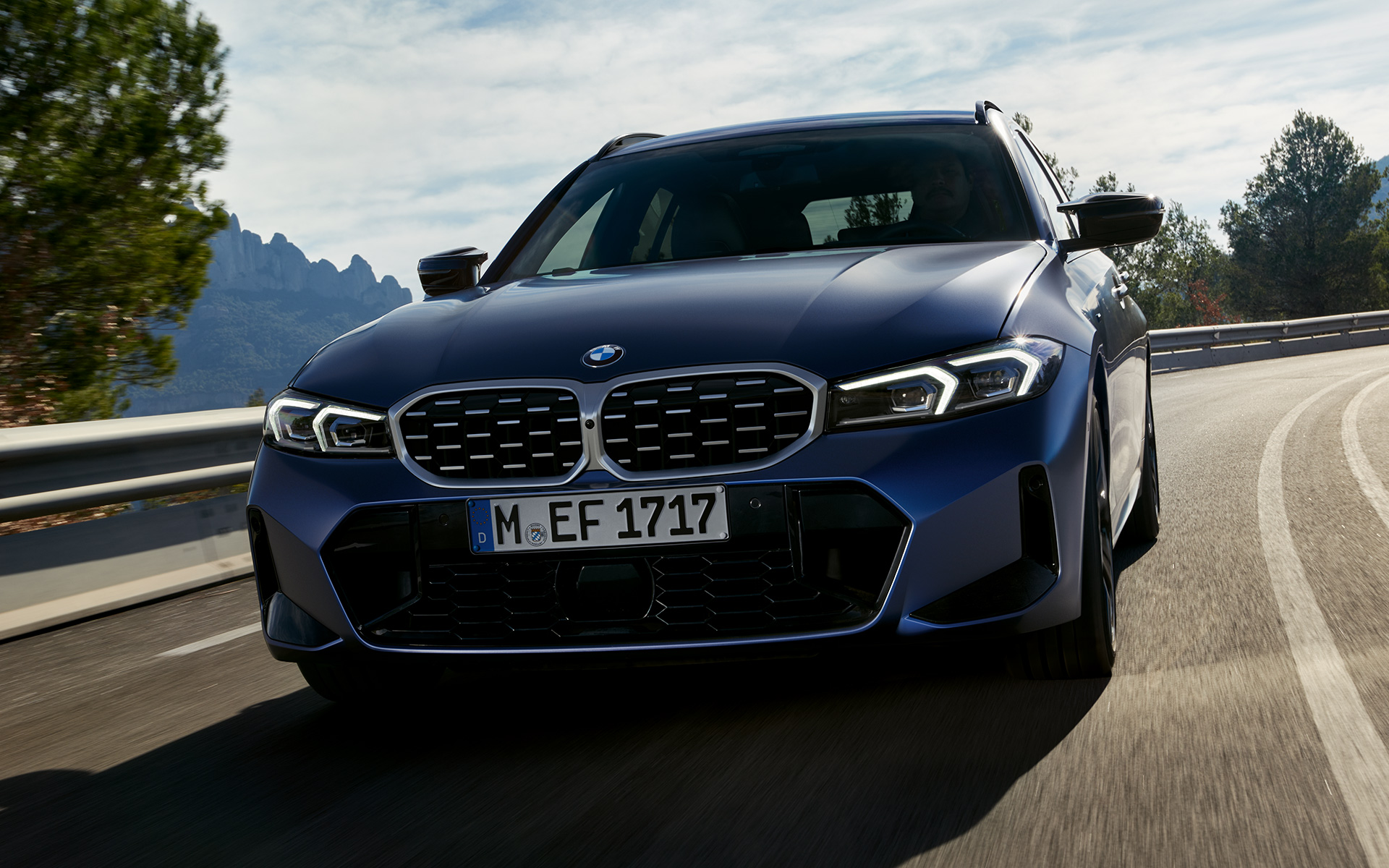 Vista frontale in movimento su strada della BMW M340i xDrive Touring G21 Vista frontale in movimento su strada della BMW M340i xDrive Touring G21 Frozen Tanzanite Blue