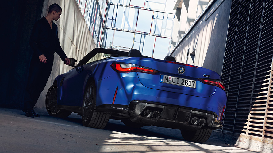BMW M4 Competition Cabrio con M xDrive G83 2021 vista posteriore a tre quarti BMW M4 Competition Cabrio con M xDrive G83 2021 BMW Individual Frozen Portimao Blue metallizzato vista posteriore a tre quarti con uomo