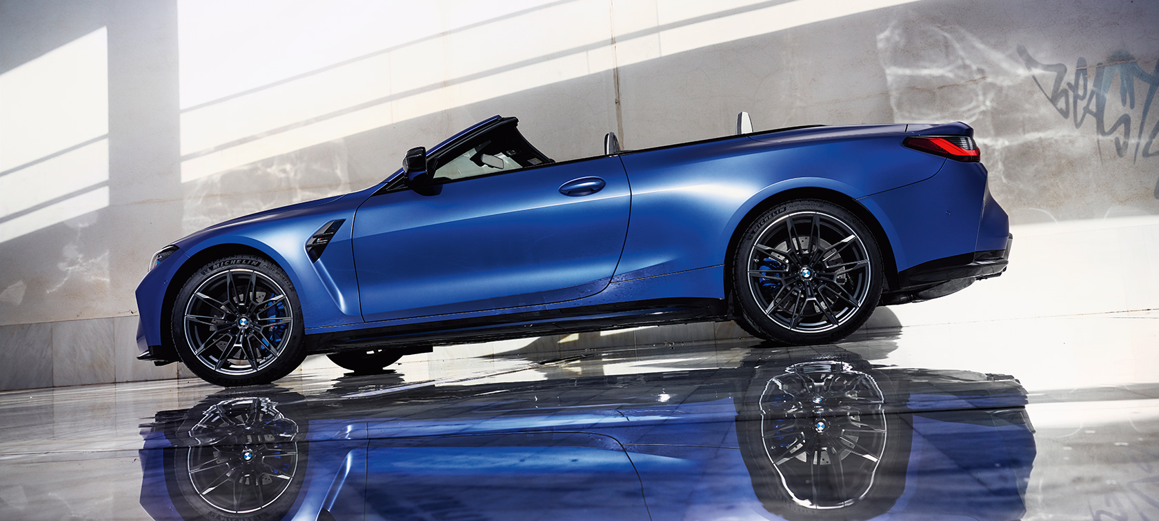BMW M4 Competition Cabrio con M xDrive G83 2021 vista anteriore a tre quarti in movimento BMW M4 Competition Cabrio con M xDrive G83 2021 BMW Individual Frozen Portimao Blue metallizzato vista anteriore a tre quarti in movimento