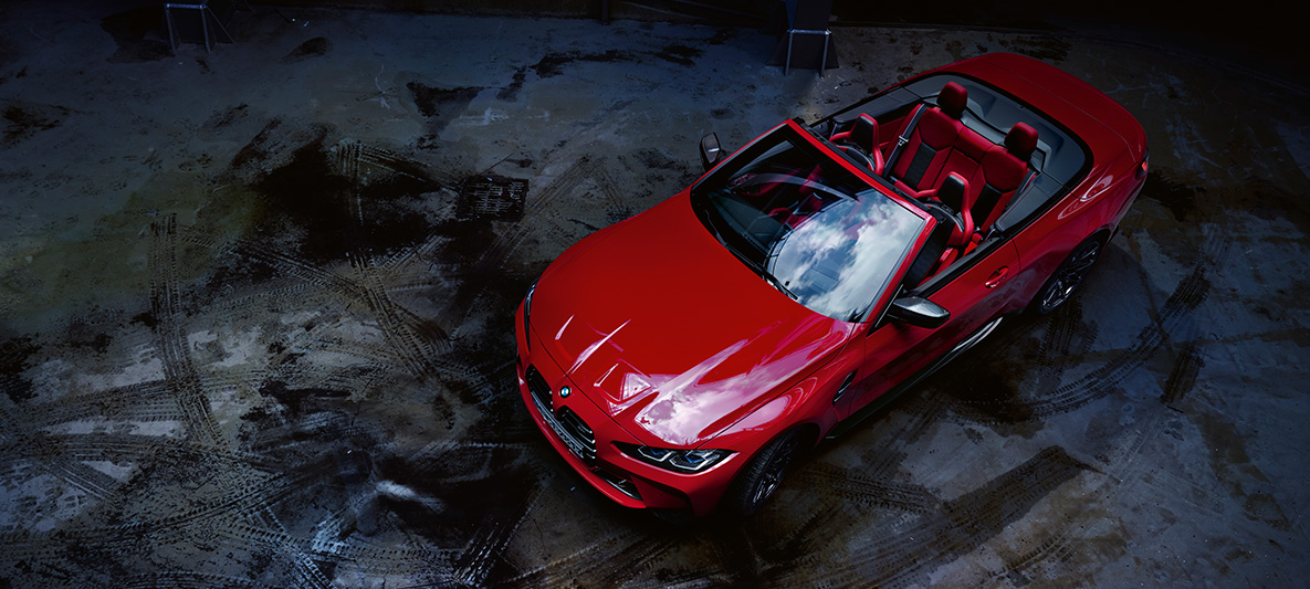 BMW Individual Imola Red metallizzato BMW M4 Competition Cabrio con M xDrive G83 2021 BMW M4 Competition Cabrio con M xDrive G83 2021 BMW Individual Imola Red metallizzato vista anteriore a tre quarti dall’alto con capote in stoffa aperta