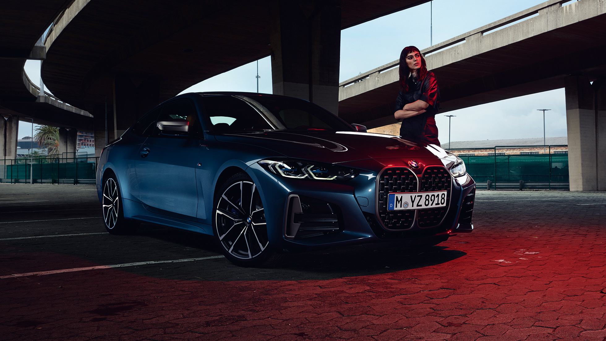Modella accanto alla BMW M440i xDrive Coupé G22 2020 in vista laterale a tre quarti BMW M440i xDrive Coupé Arctic Race Blue metallizzato G22 2020 vista laterale a tre quarti con modella