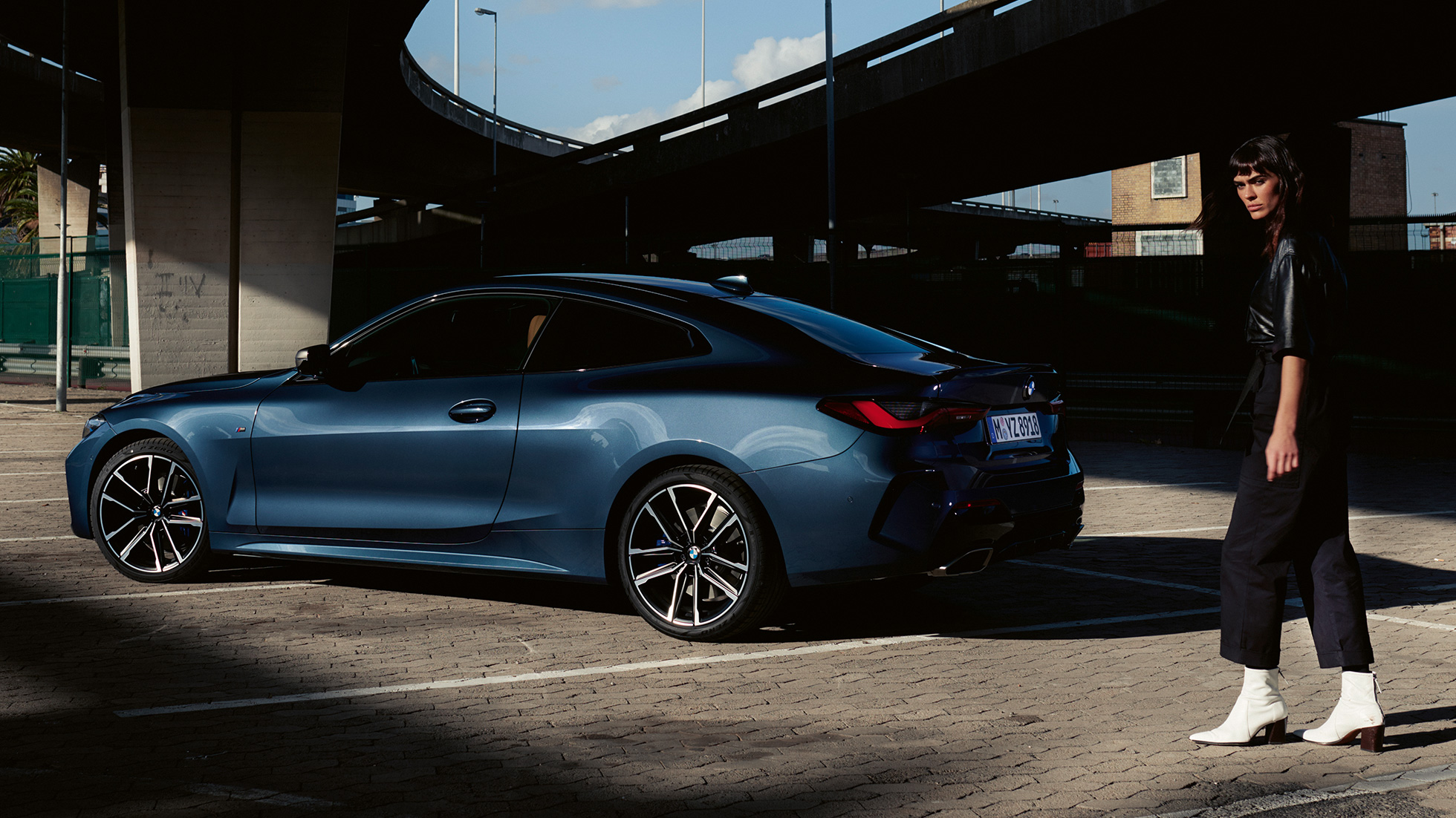 Vista posteriore a tre quarti con modella della BMW M440i xDrive Coupé G22 2020 BMW M440i xDrive Coupé Arctic Race Blue metallizzato G22 2020 vista posteriore a tre quarti con modella