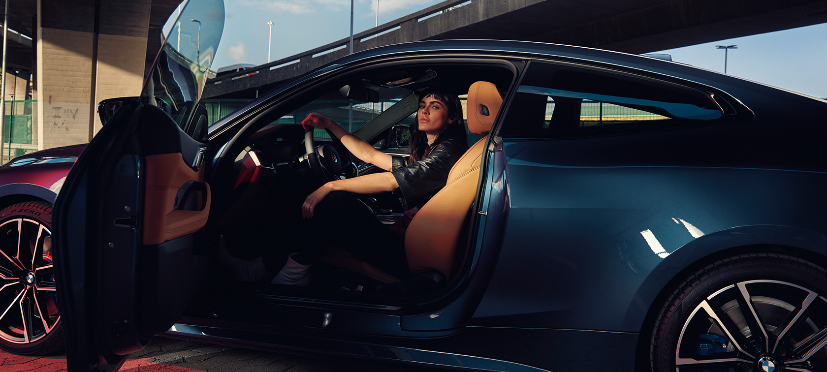 Vista laterale con modella della BMW M440i xDrive Coupé G22 2020 BMW M440i xDrive Coupé G22 2020 Arctic Race Blue metallizzato vista laterale, modella seduta in auto con portiera aperta
