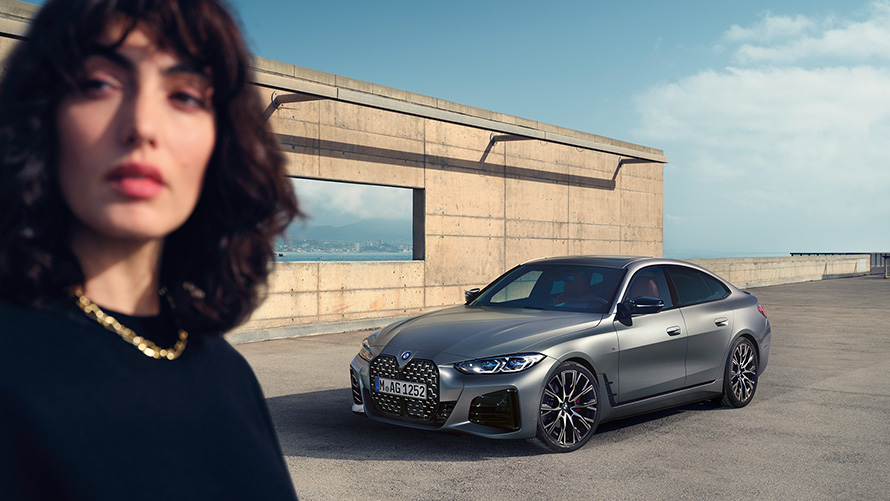 BMW M440i xDrive Gran Coupé G26 2021 Vista anteriore a tre quarti con modella BMW M440i xDrive Gran Coupé G26 2021 Frozen Pure Grey metallizzato Vista anteriore a tre quarti con modella