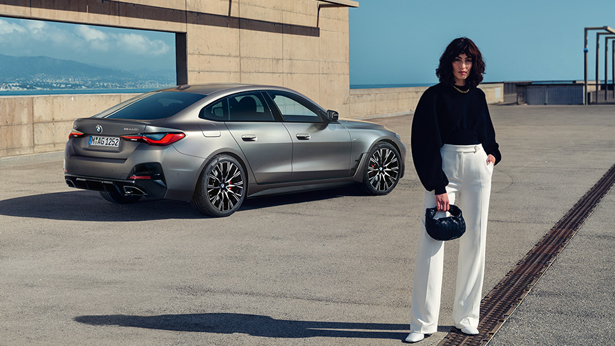 BMW M440i xDrive Gran Coupé G26 2021 Vista posteriore a tre quarti con modella BMW M440i xDrive Gran Coupé G26 2021 Frozen Pure Grey metallizzato Vista posteriore a tre quarti con modella