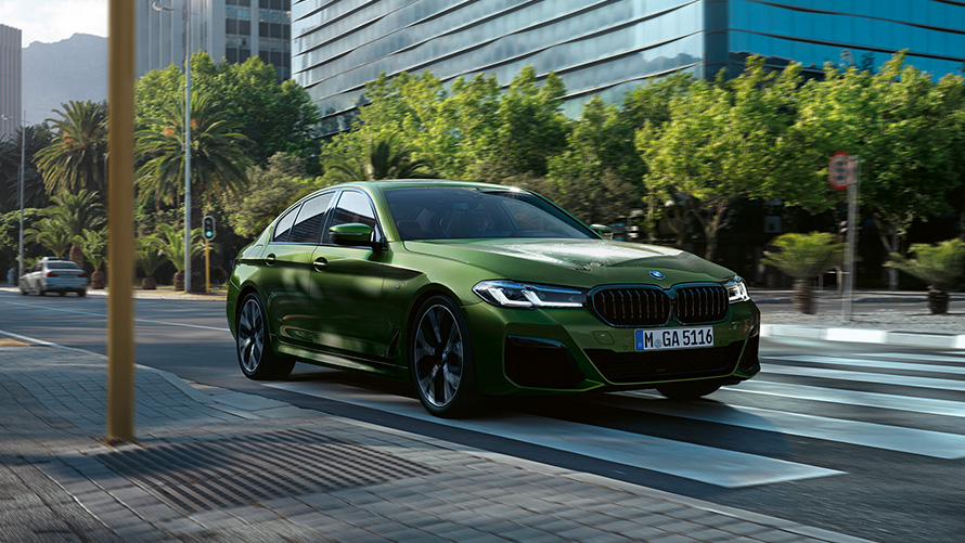 BMW M550i xDrive Berlina G30 LCI Facelift 2020 Hermes Green BMW Individual metallizzato vista anteriore a tre quarti in movimento