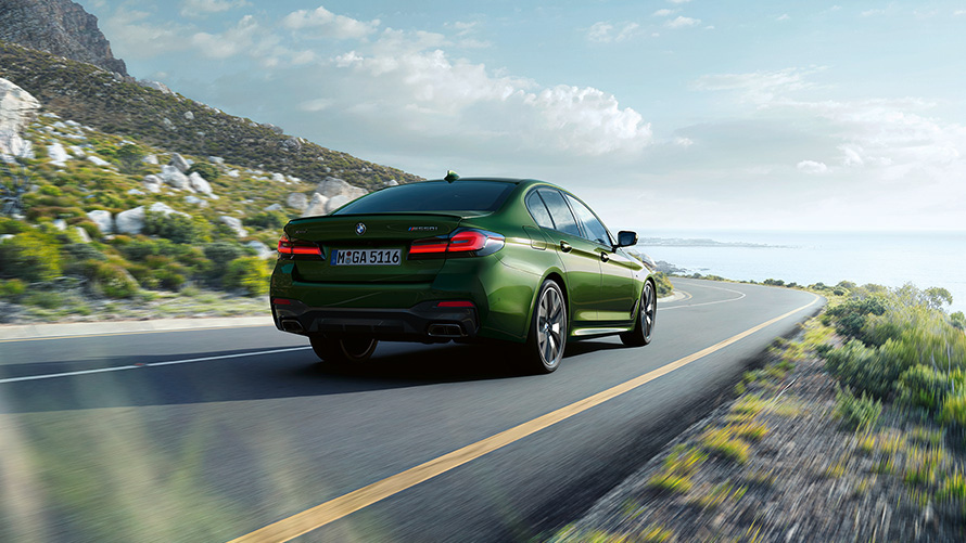 BMW M550i xDrive Berlina G30 LCI Facelift 2020 Hermes Green BMW Individual metallizzato vista posteriore a tre quarti in movimento