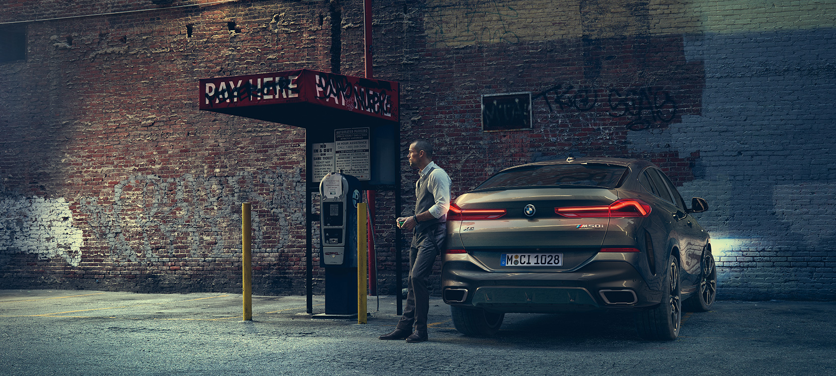 Posteriore della BMW X6 M50i. Un uomo è appoggiato sul posteriore della BMW X6 M50i.