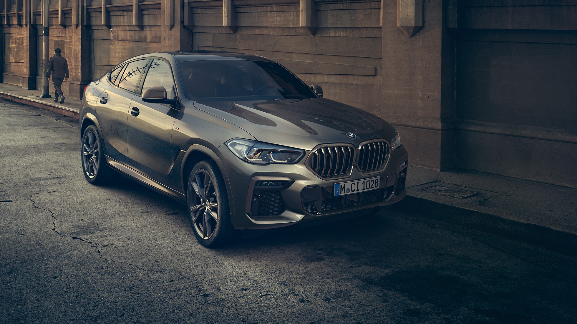 BMW X6 M50i ferma. Vista anteriore a tre quarti ferma della BMW X6 M50i in ambiente urbano.