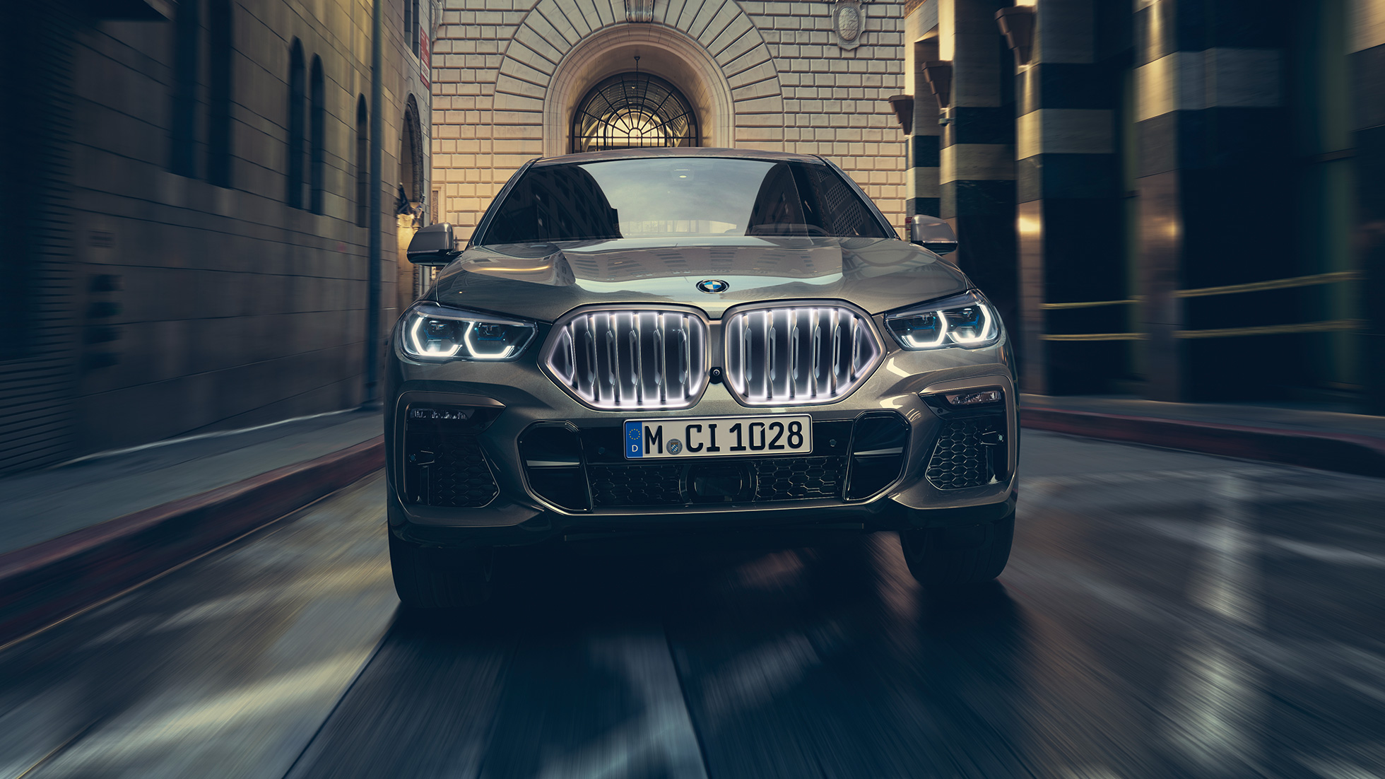 BMW X6 M50i con doppio rene BMW “Iconic Glow”. Vista anteriore della BMW X6 M50i in ambiente urbano.