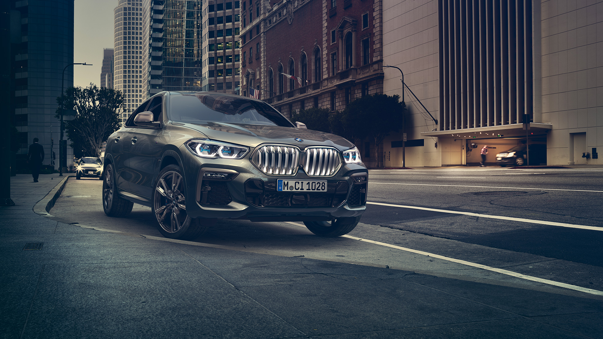 BMW X6 M50i ferma. Vista anteriore a tre quarti ferma della BMW X6 M50i in ambiente urbano.