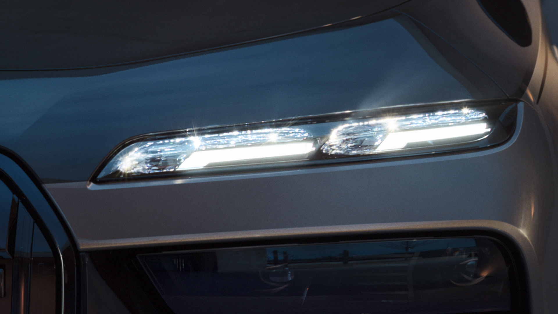 Gruppi ottici anteriori in cristallo BMW “Iconic Glow” della BMW M760e xDrive Berlina G70 Primo piano dei gruppi ottici anteriori in cristallo BMW “Iconic Glow” accesi della BMW M760e xDrive Berlina G70 in bicolore BMW Individual Sapphire Black metallizzato e BMW Individual Dravit Grey metallizzato