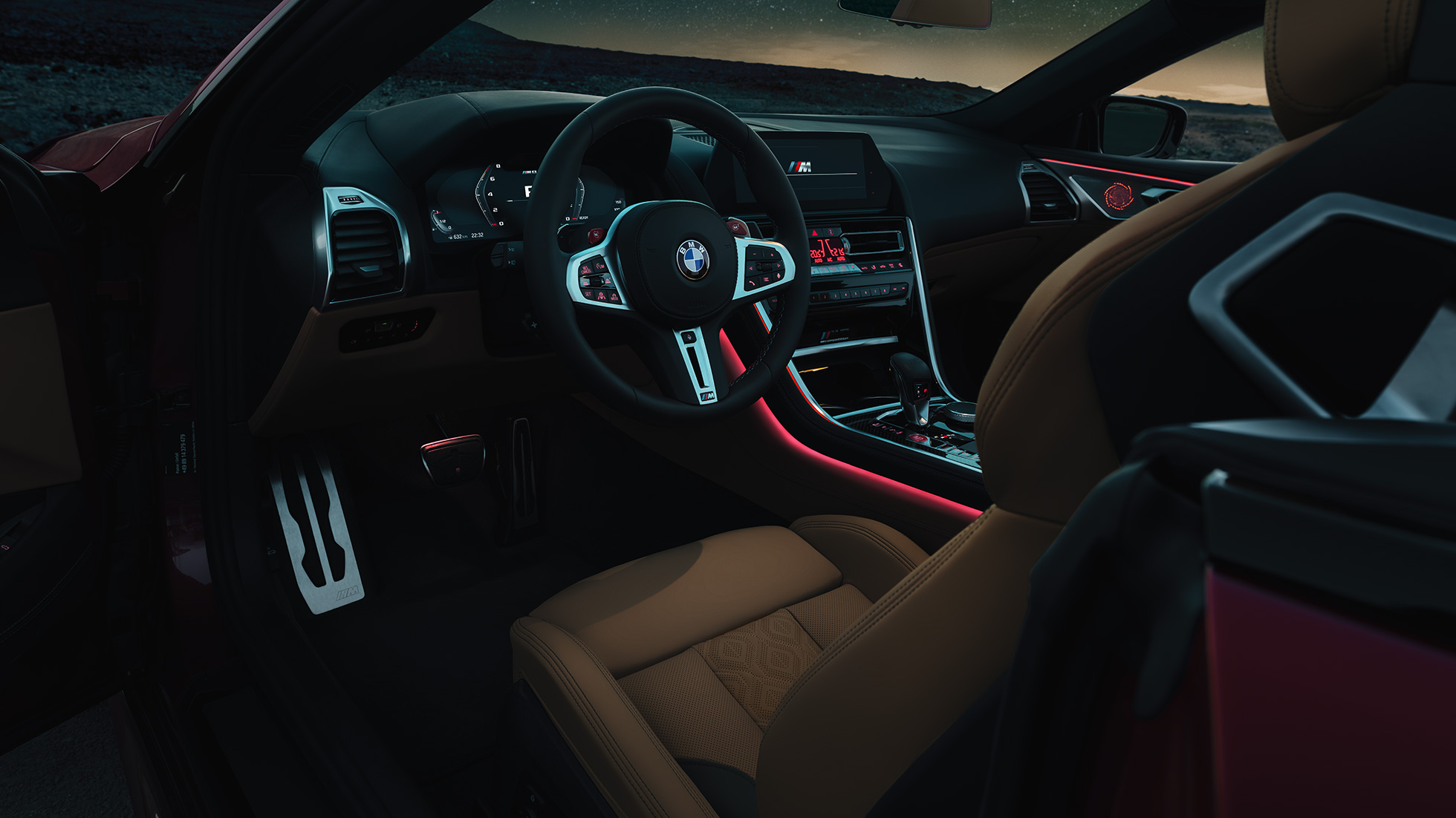 BMW M8 Competition Cabrio, cockpit F91. BMW M8 Competition Cabrio, cockpit di notte con volante in pelle M e luce ambiente rossa F91.