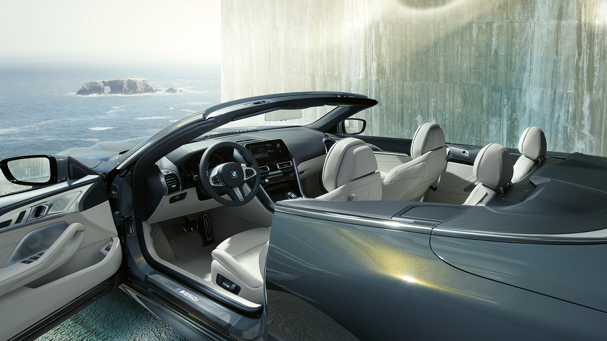 BMW M850i xDrive Cabrio, interni G14. BMW M850i xDrive Cabrio in Dravit Grey metallizzato con capote aperta, interni con volante in pelle M ed equipaggiamento in pelle Merino BMW Individual Ivory White G14.