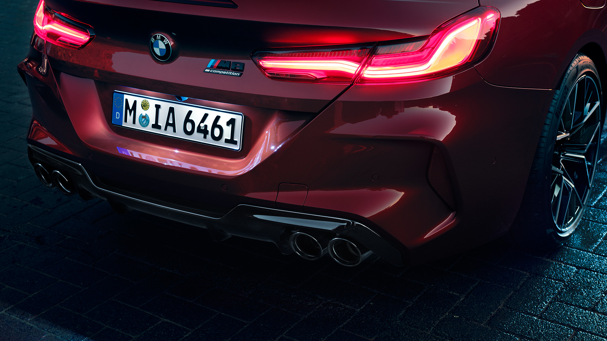 BMW M8 M Competition Cabrio, primo piano del posteriore F91. BMW M8 Competition Cabrio in Motegi Red metallizzato, primo piano del posteriore con gruppi ottici a LED e M8 Competition Badge F91.