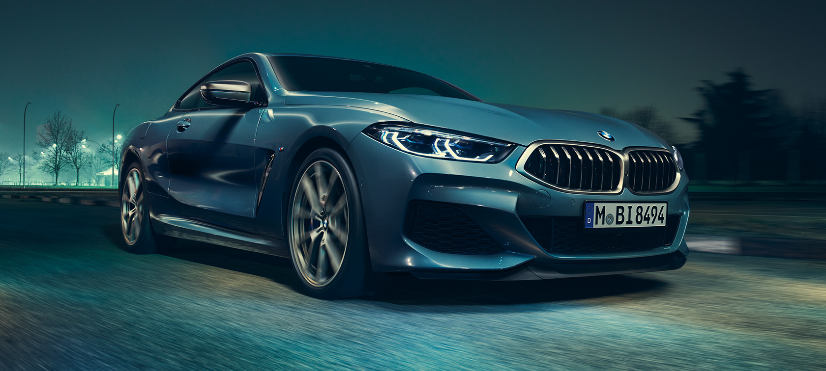 BMW M850i xDrive Coupé, vista frontale di tre quarti G15. BMW M850i xDrive Coupé in Barcelona Blue metallizzato in marcia, vista frontale di tre quarti G15.