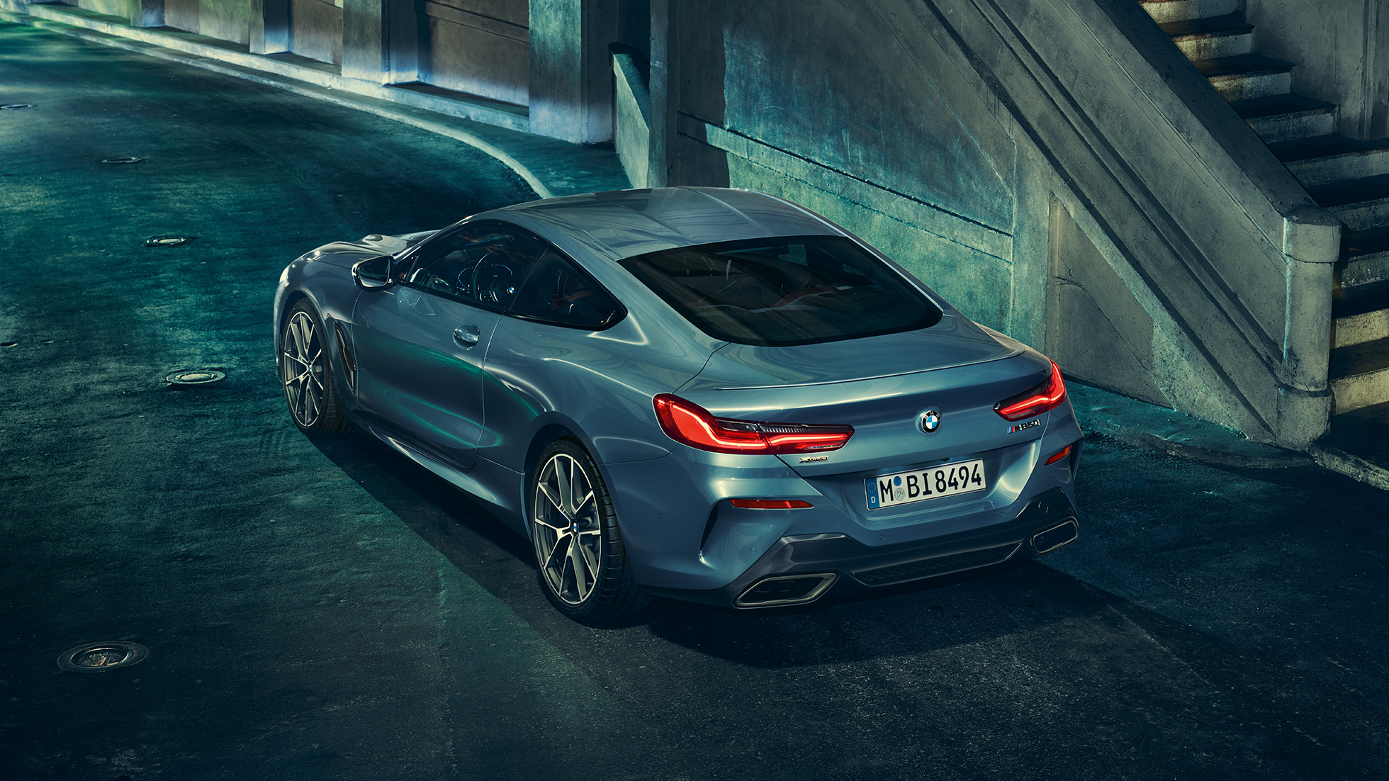 BMW M850i xDrive Coupé, vista posteriore di tre quarti da sinistra G15. BMW M850i xDrive Coupé in Barcelona Blue metallizzato, vista posteriore di tre quarti da sinistra, in sosta di notte G15.