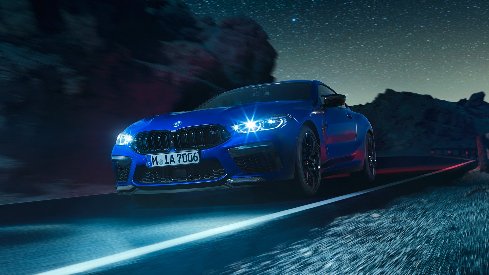 BMW M8 M Coupé in marcia, vista frontale di tre quarti F92. BMW M8 Competition Coupé in Marina Bay Blue metallizzato con fari a LED accesi, vista frontale di tre quarti, in marcia di notte F92.