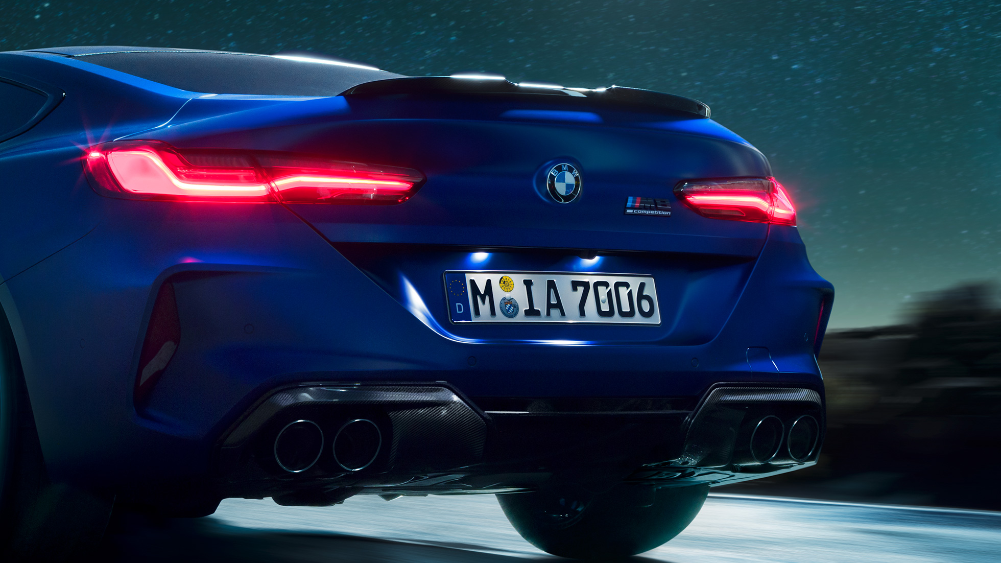 Diffusore M in carbonio nero F92. BMW M8 Competition Coupé in Marina Bay Blue metallizzato, primo piano del posteriore di notte con diffusore M in carbonio nero F92.