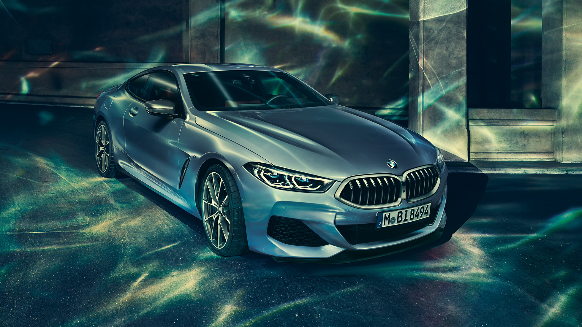 BMW M850i xDrive Coupé, vista frontale di tre quarti da sinistra G15. BMW M850i xDrive Coupé in Barcelona Blue metallizzato, vista frontale di tre quarti da sinistra, in sosta davanti a un edificio G15.