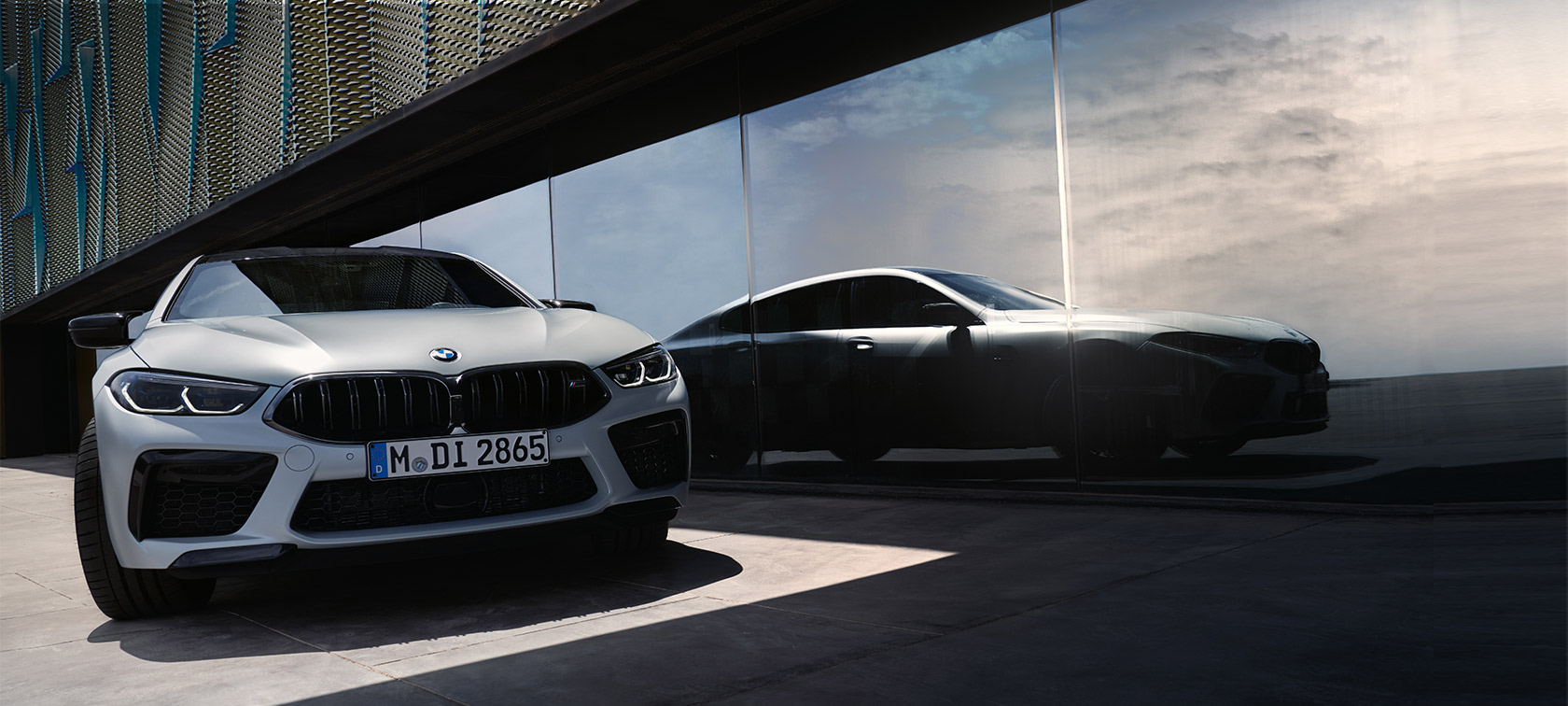 Vista anteriore della BMW M8 Competition Gran Coupé F93 LCI Facelift 2022 BMW M8 Competition Gran Coupé F93 LCI Facelift 2022 BMW Individual BMW Individual Frozen Brilliant White metallizzato Vista anteriore con l’immagina specchiata della silhouette su una vetrina