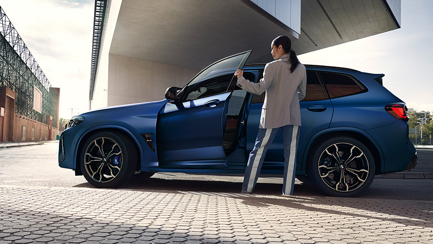 BMW X3 M Competition F97 LCI 2021 Vista laterale con portiera aperta e modella BMW X3 M Competition F97 LCI Facelift 2021 Frozen Marina Bay Blue metallizzato Vista laterale con portiera aperta e modella