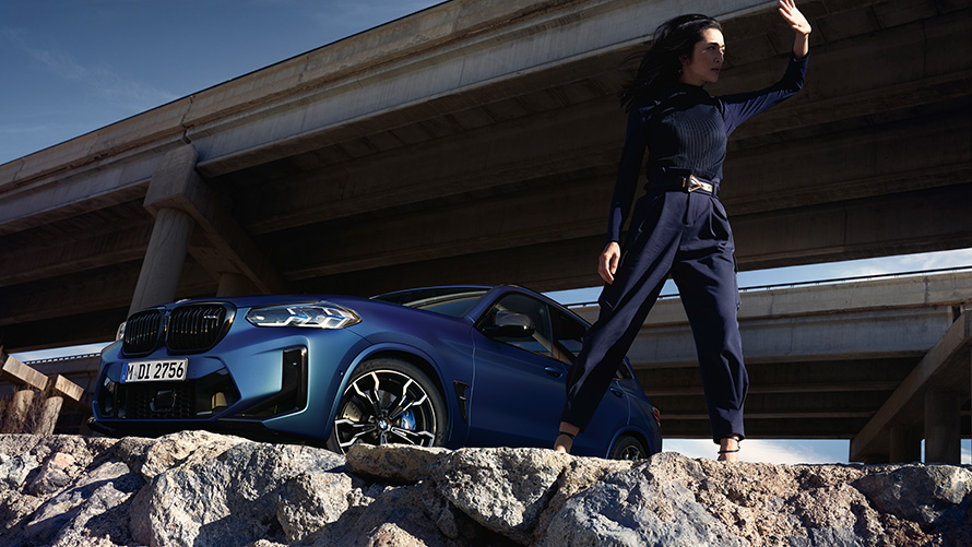 BMW X3 M Competition F97 LCI Facelift 2021 Vista anteriore a tre quarti con modella BMW X3 M Competition F97 LCI Facelift 2021 BMW Individual Frozen Portimao Blue metallizzato Vista anteriore a tre quarti con modella