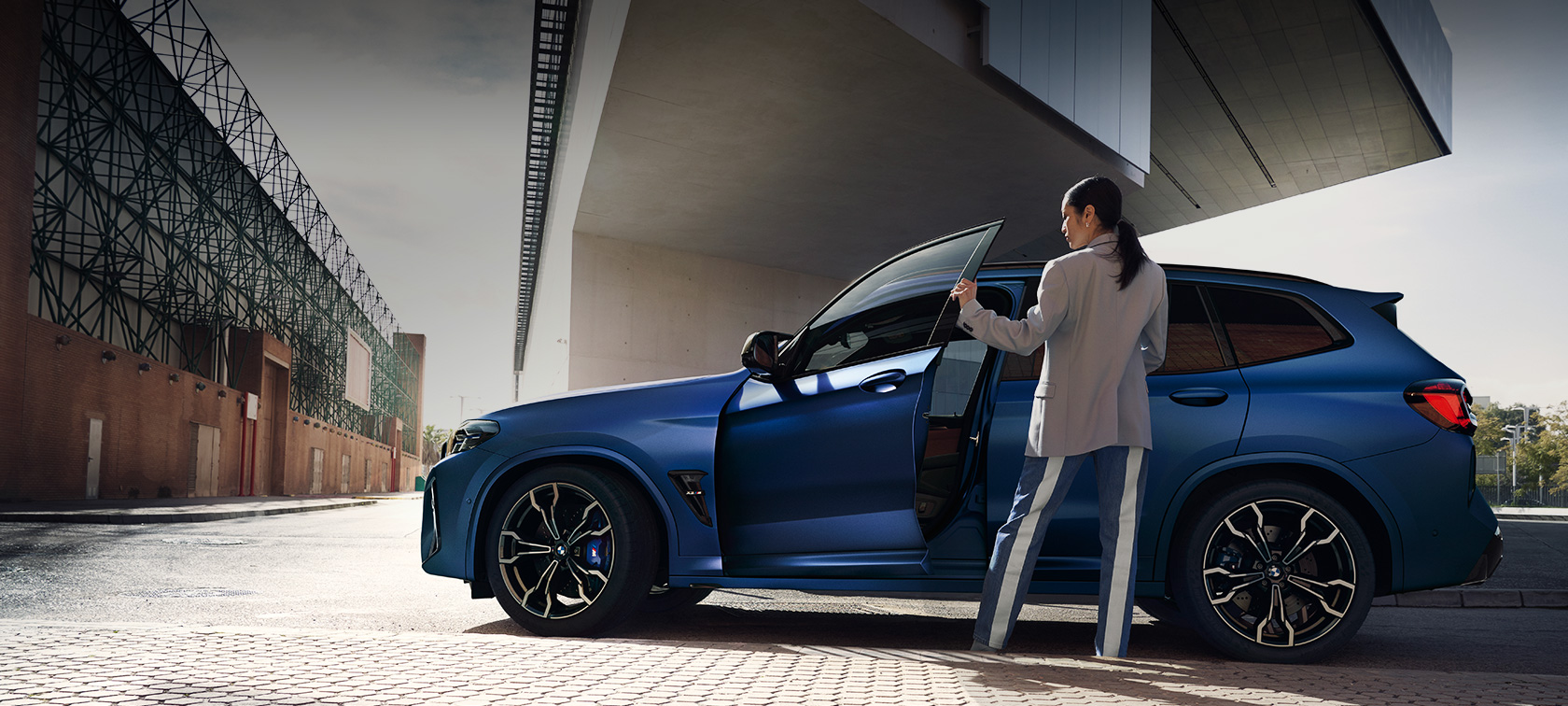 BMW X3 M Competition F97 LCI Facelift 2021 Vista laterale da ferma BMW X3 M Competition F97 LCI Facelift 2021 BMW Individual Frozen Portimao Blue metallizzato Vista laterale da ferma con portiera aperta e modella