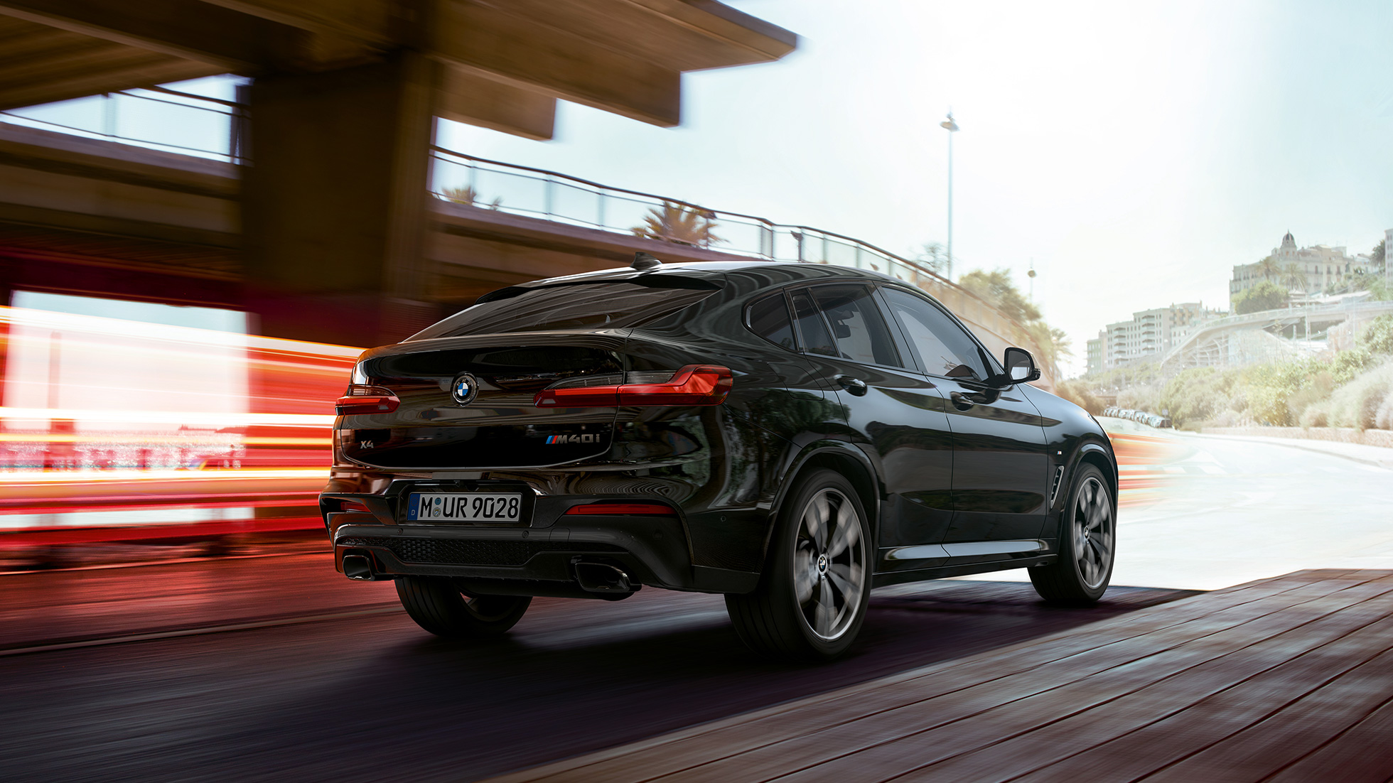 BMW X4 M40i, vista anteriore a tre quarti G02. BMW X4 M40i in Sapphire Black metallizzato, in movimento, esterni, vista anteriore a tre quarti con strisce di luce G02.