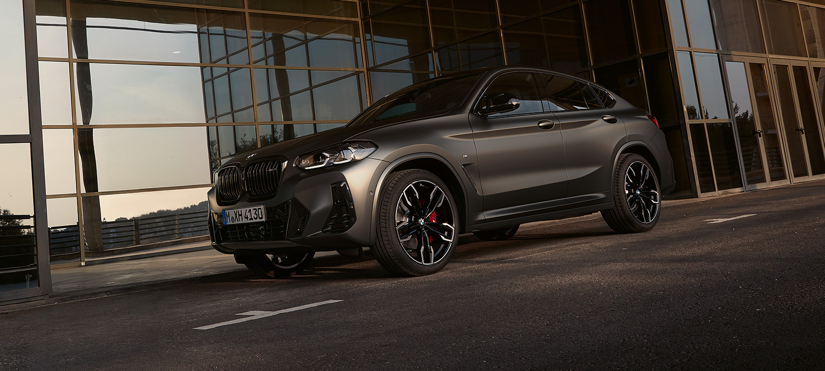 Vista anteriore a tre quarti della BMW X4 M40i G02 LCI 2021 Facelift BMW X4 M40i G02 LCI 2021 Facelift Vista anteriore a tre quarti davanti a facciata di vetro