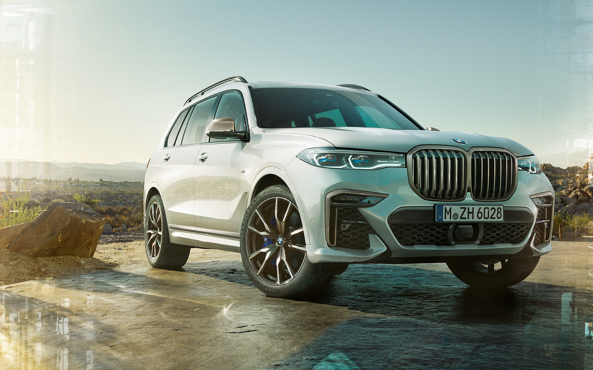 BMW X7 M50i G07 2019 Mineral White ferma con paesaggio di campagna sul fondo BMW X7 M50i G07 2019 Mineral White Vista anteriore a tre quarti ferma con paesaggio di campagna sul fondo