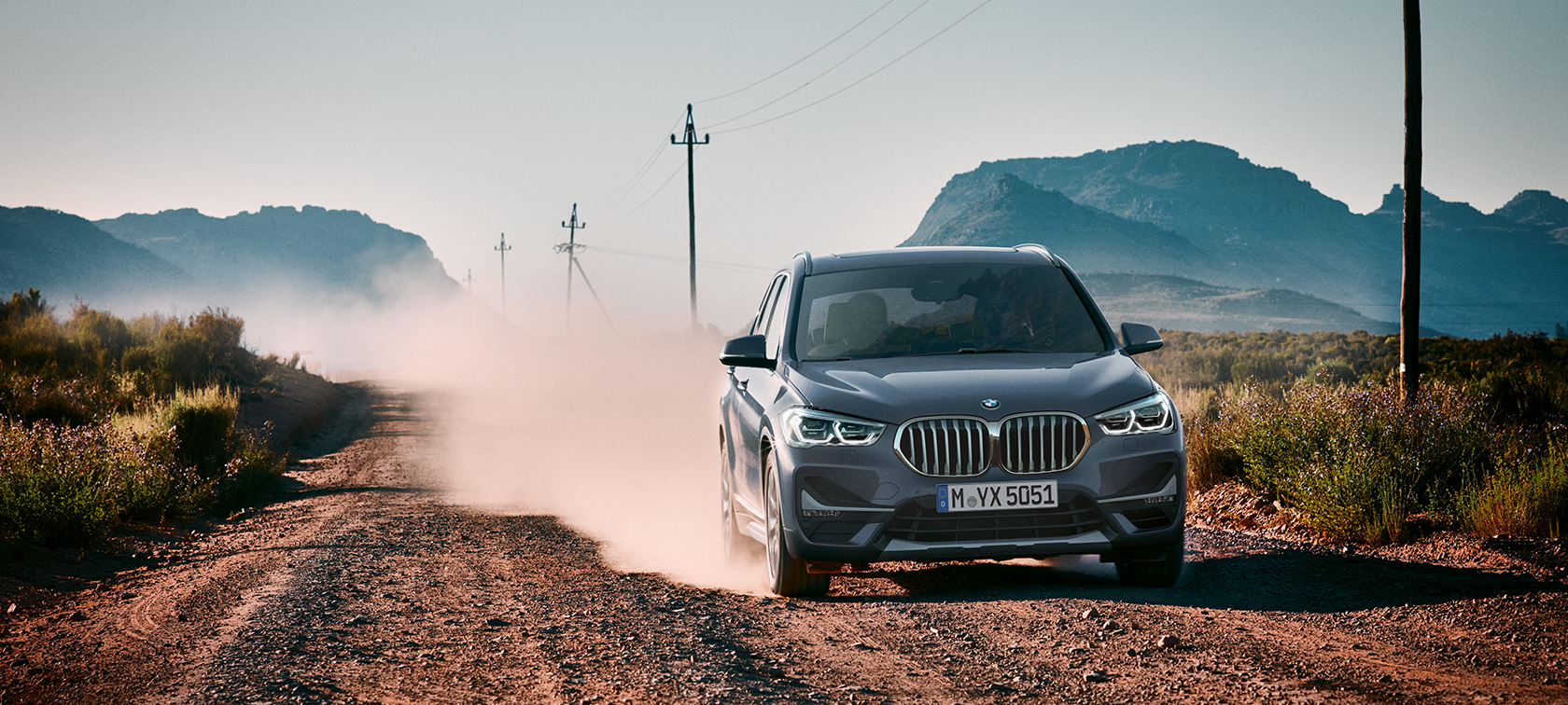 Nuova BMW X1, vista posteriore a tre quarti. Nuova BMW X1, vista posteriore a tre quarti in movimento in un paesaggio montano.