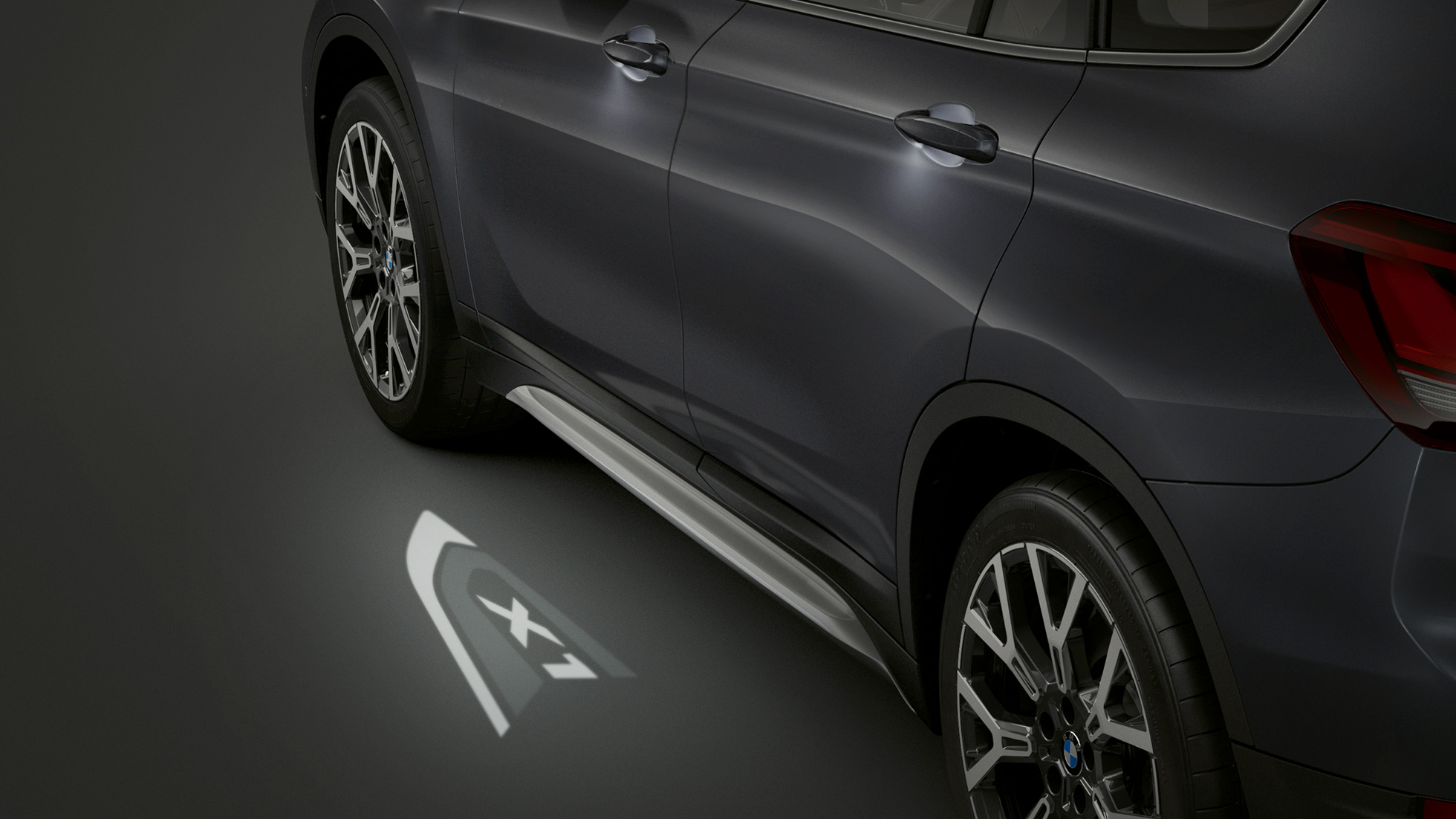BMW X1, proiezione a LED del logo “X1”. BMW X1, vista laterale con primo piano della proiezione a LED del logo “X1”.