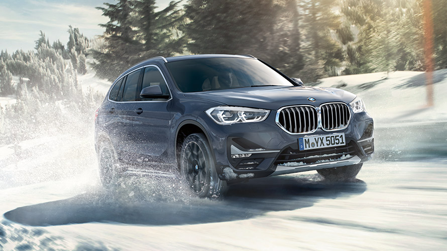 BMW X1 xDrive20i F48 LCI in BMW Individual Storm Bay metallizzato, in movimento con paesaggio invernale BMW X1 xDrive20i F48 LCI in BMW Individual Storm Bay metallizzato, in movimento con paesaggio invernale