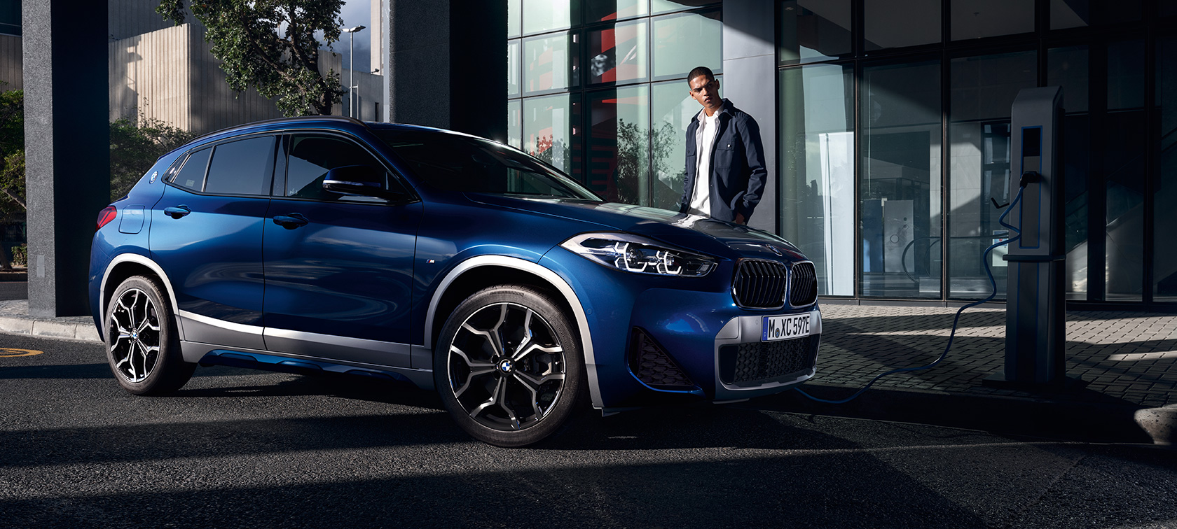 BMW X2 xDrive25e F39 ibrida Plug-in vista laterale a tre quarti presso la stazione di ricarica BMW X2 xDrive25e F39 ibrida Plug-in vista laterale a tre quarti presso la stazione di ricarica con fotomodella