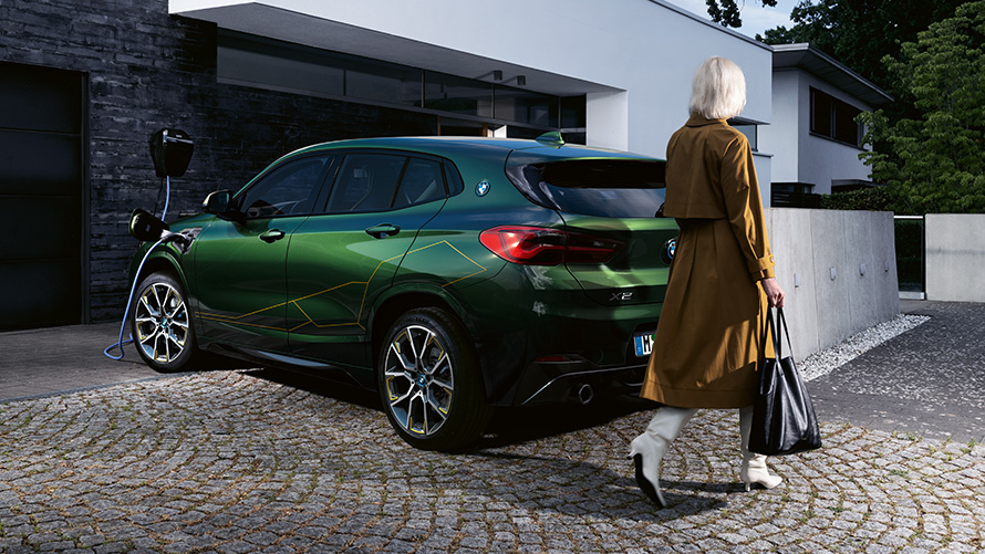 BMW X2 F39 Sanremo Green metallizzato vista posteriore a tre quarti con modella BMW X2 F39 Sanremo Green metallizzato vista posteriore a tre quarti con modella