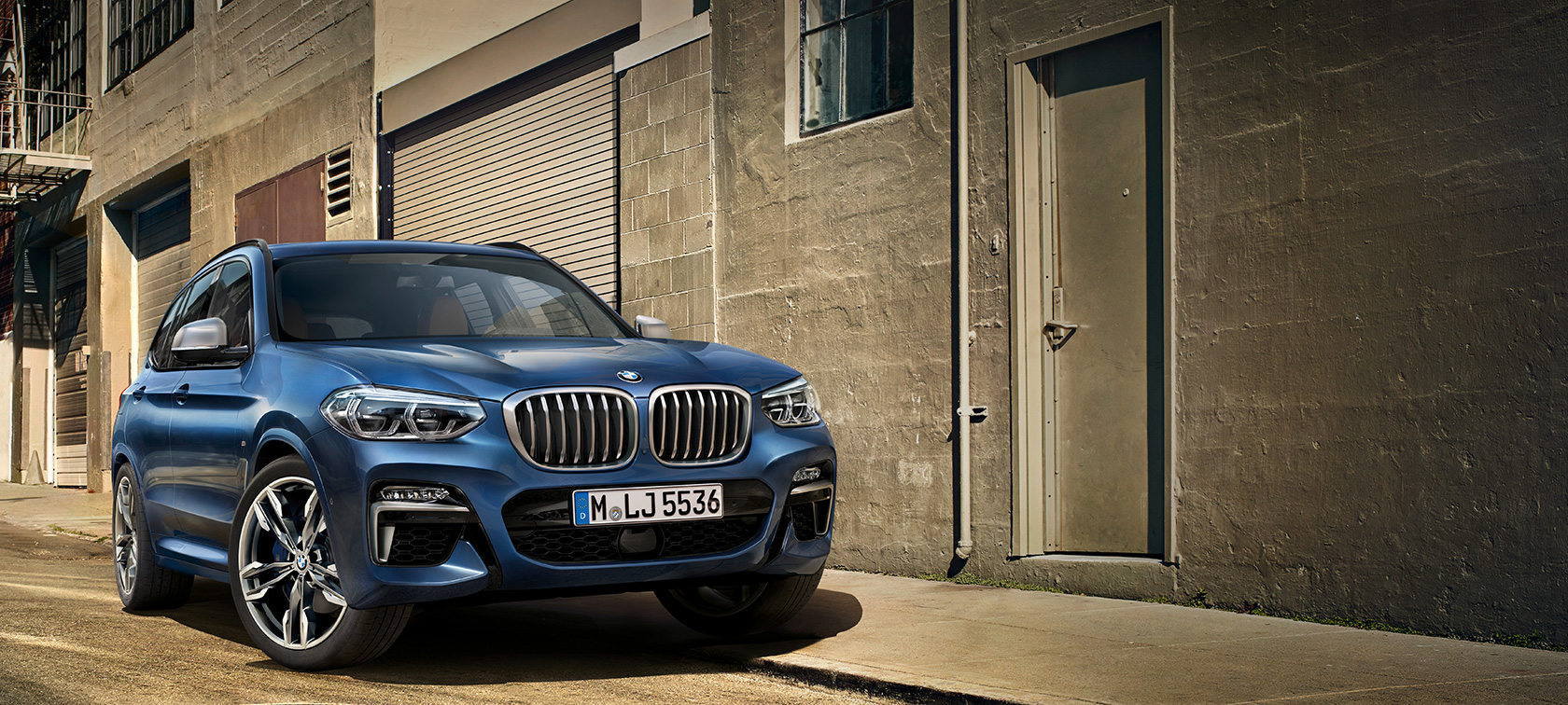 BMW X3 M40i, ripresa da ferma davanti ad una facciata BMW X3 M40i, ripresa da ferma davanti ad una facciata