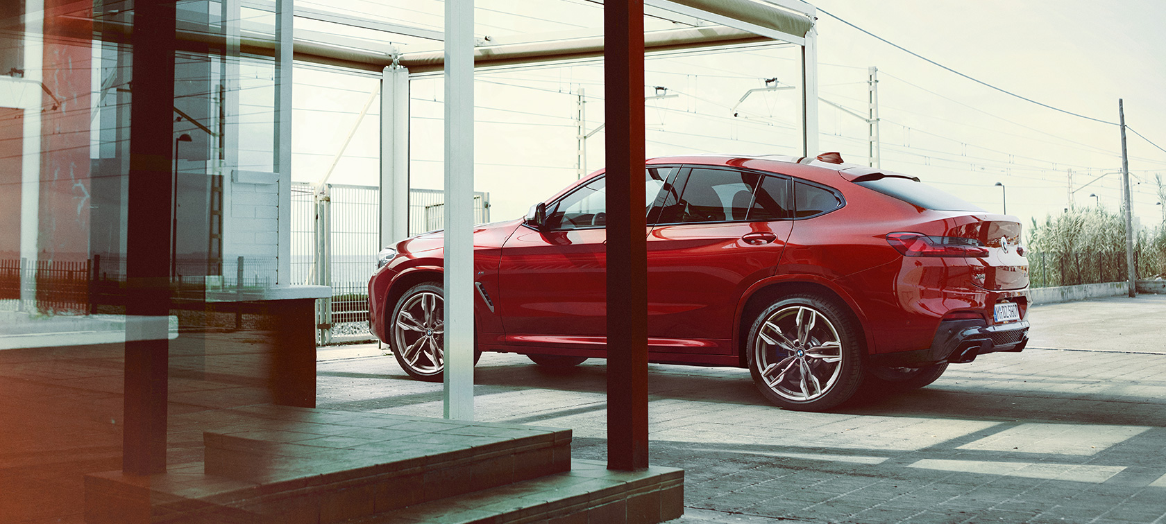 BMW X4 Vista laterale G02 BMW X4 M40i G02 2018 Flamenco Red brilliant effect Vista laterale in parcheggio