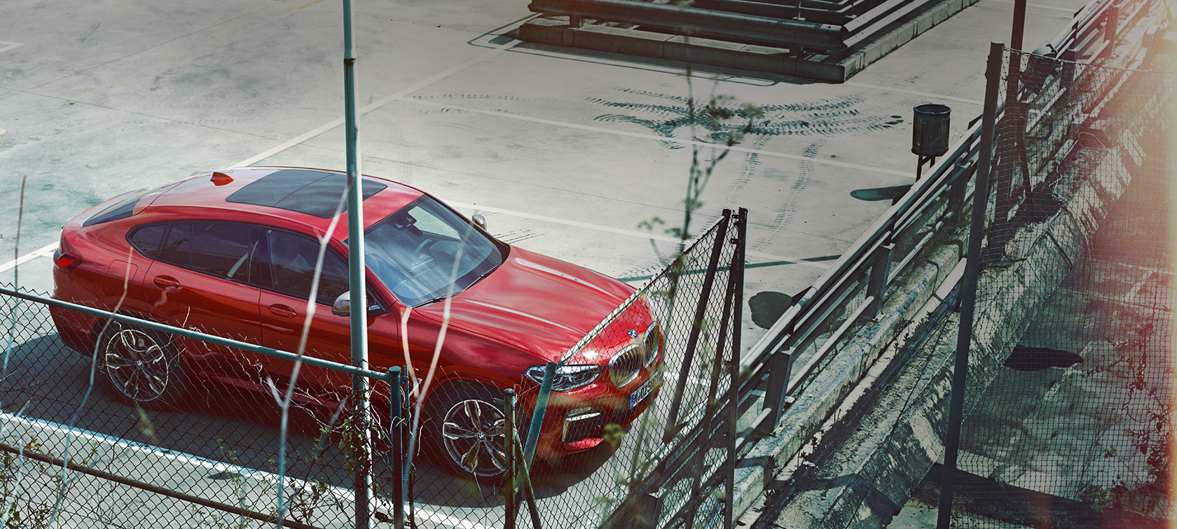 BMW X4 SUV in manovra di parcheggio G02 BMW X4 SUV G02 2018 Flamenco Red brilliant effect parcheggiata nell’autosilo con prospettiva a volo di uccello