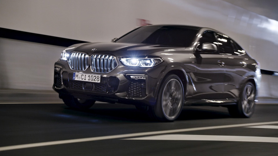 Vista anteriore a tre quarti della BMW X6 G06 2019 Vista anteriore a tre quarti della BMW X6 G06 2019 in movimento con sfondo urbano