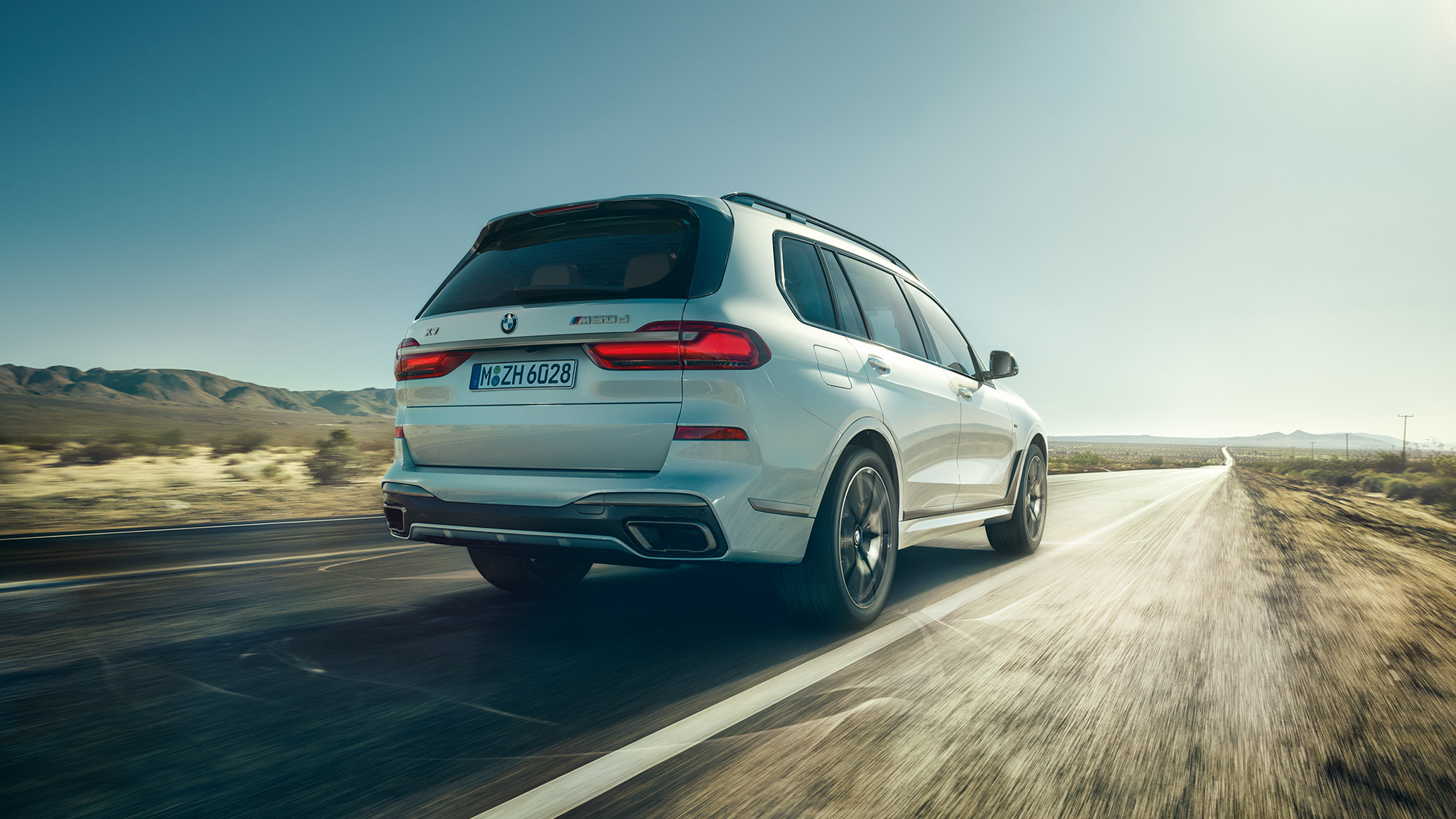 Nuova BMW X7 M50d, inquadratura posteriore Nuova BMW X7 M50d: guida di una BMW X7 bianca con inquadratura posteriore