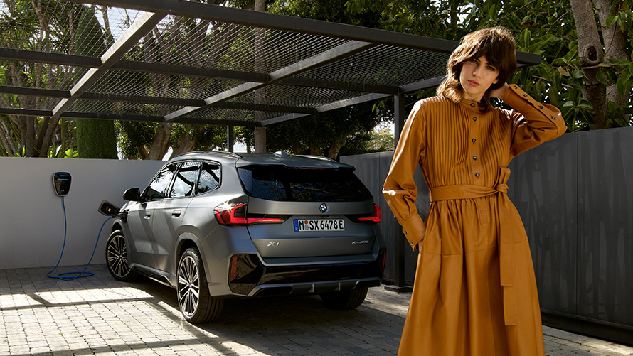 Vista posteriore in ricarica della BMW X1 ibrida Plug-in 2022 U11 con modella Vista posteriore in ricarica della BMW X1 ibrida Plug-in 2022 U11 con modella