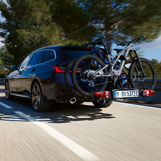 BMW Serie 3 Touring G21 PHEV Vista posteriore a tre quarti in movimento con biciclette