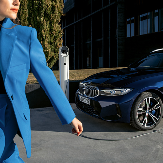 BMW in ricarica con una donna che passa in primo piano