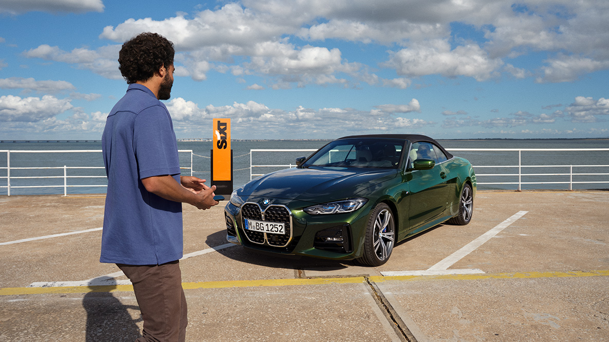 BMW Add-On Mobility App Video BMW Add-On Mobility App Video Uomo con smartphone in mano davanti a una BMW Serie 4 Cabrio e scritta SIXT sullo sfondo