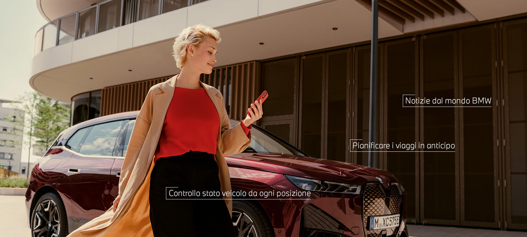 Donna davanti a BMW iX che usa My BMW App su smartphone